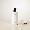 Byredo Mojave Ghost Shampoo 450ml lifestyle on cream marble with magnolia