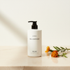 Byredo Bal D'Afrique Shower Gel 450ml lifestyle flat lay on cream marble with marigold flowers