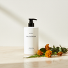 Byredo Bal D'Afrique Body Lotion 450ml lifestyle flat lay on cream marble with marigold flowers